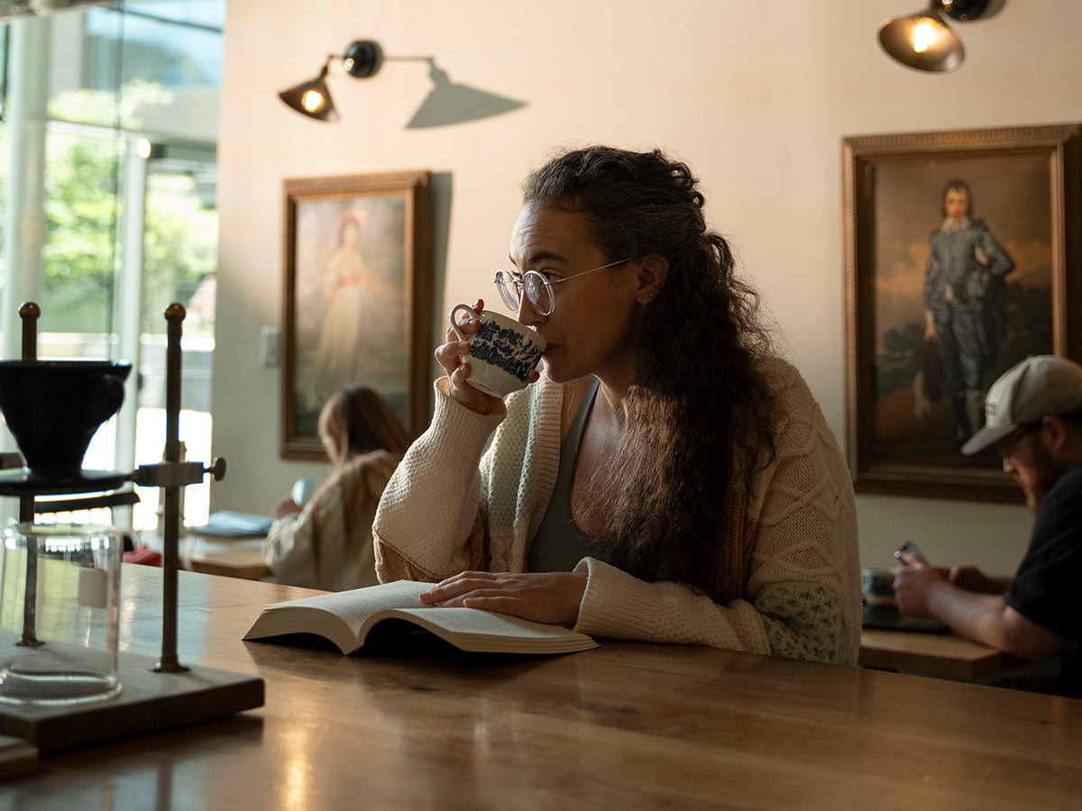 Woman sipping coffee while reading a book